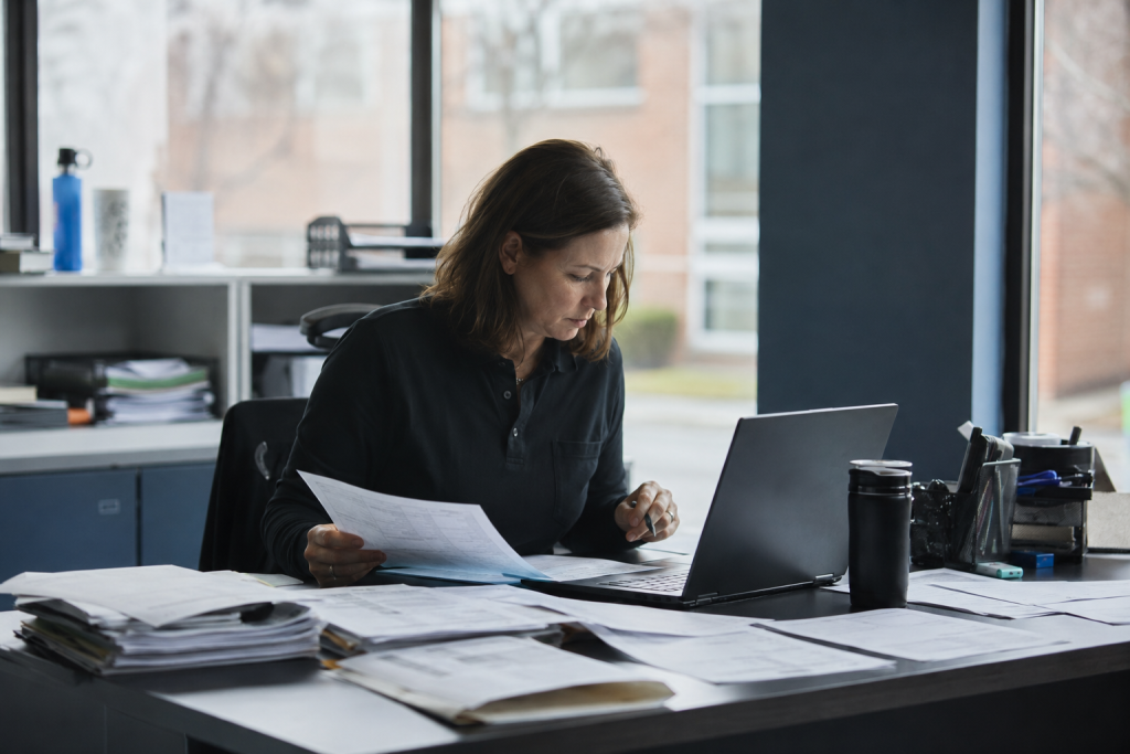 Handschriftliche Stundenzettel und Excel-Listen auf einem Bürotisch