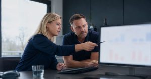 Objektleiterin und Geschäftsführer analysieren den Deckungsbeitrag pro Objekt am Bildschirm